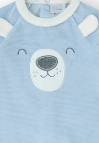 Prenda para bebé de color azul claro con un diseño de cara de oso polar con detalles bordados, acentos blancos de felpa en los hombros y textura suave.