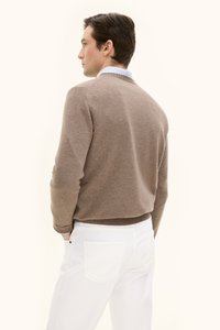 Ruskea neulepaita, jossa on pyöreä kaula-aukko ja ribattu helma, yhdistetty valkoisiin housuihin. Pehmeä rakenne ja minimaalinen muotoilu, kuvattu takaa.