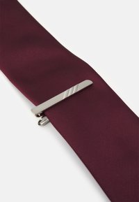 Cravat bordeaux, realizată dintr-un material neted, cu un clips pentru cravată argintiu, cu dungi diagonale și un design simplu.