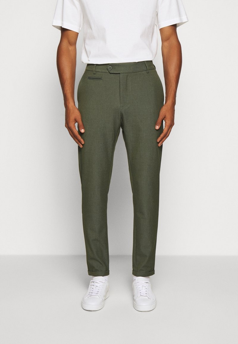 Olivgröna chinos i textil med strukturerad yta, med slim fit, knappstängning och sidofickor, ihop med vita sneakers.