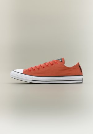 Nízke tenisky z jasne oranžového plátna s bielou gumovou špičkou a bielou podrážkou s dvoma čiernymi pruhmi a zaviazaním na šnúrky.