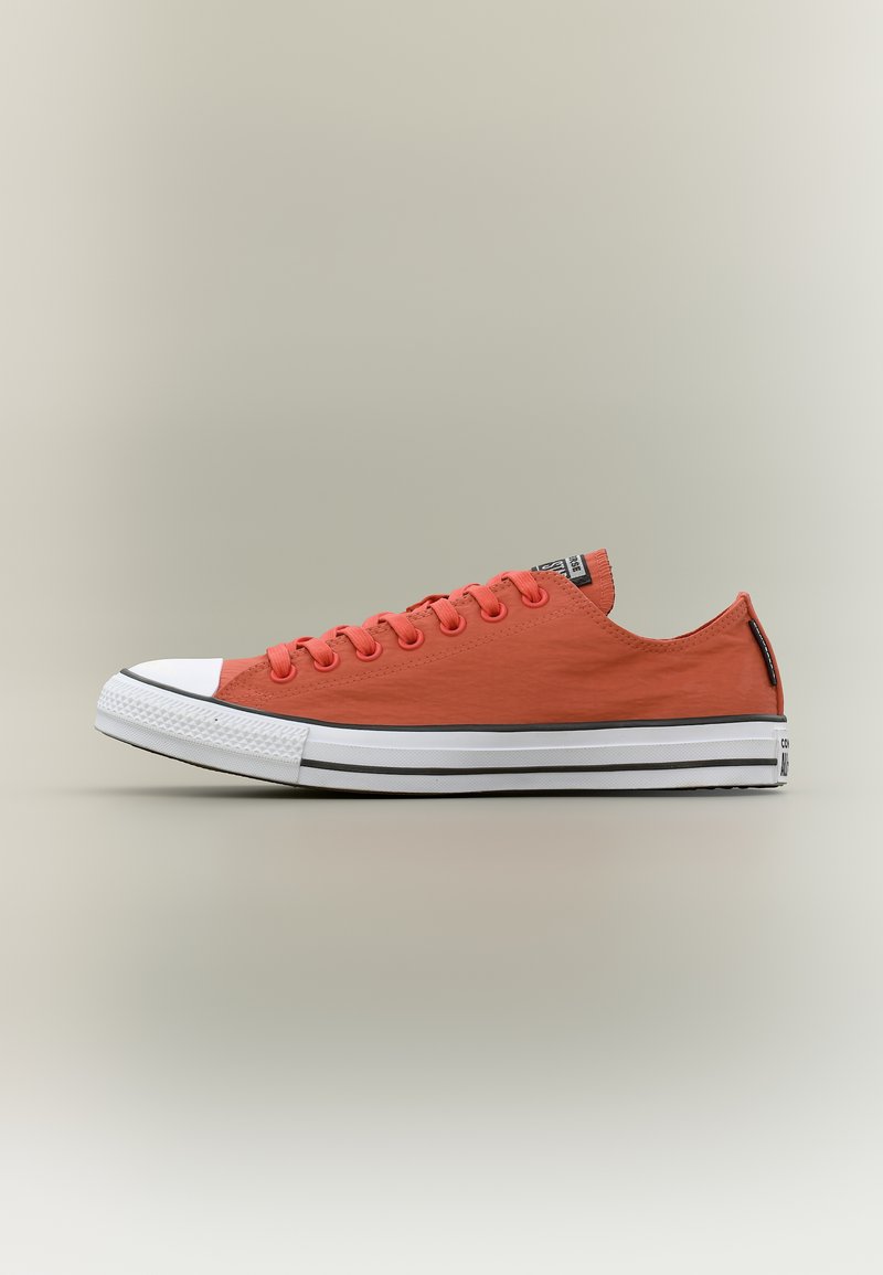 Χαμηλή εσώεψη πορτοκαλί ύφασμα αθλητικό παπούτσι με λευκή λαστιχένια μύτη και λευκή σόλα με δύο μαύρες ρίγες και κλείσιμο με κορδόνια.