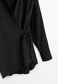 Mustat kääntöpaidat, jotka on valmistettu sileästä kankaasta. Varustettu vyötärölle solmittavalla vyöllä, pitkät hihat, joissa on hihansuut, sekä etutaskurakenne.