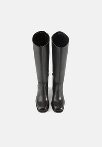 Botas de cuero negras hasta la rodilla con una textura suave, punteras cuadradas, detalles de costura sutiles y cremalleras laterales para facilitar su uso.