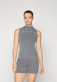 Top grigio senza maniche con collo alto, realizzato in tessuto liscio, caratterizzato da un piccolo logo sul petto, abbinato a pantaloncini a righe coordinati.