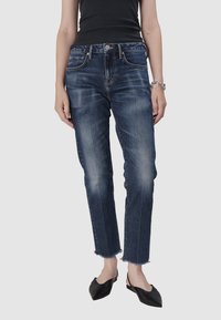 Jean en denim bleu foncé avec une légère décoloration, coupe droite et ourlet effiloché. Il présente un design à cinq poches et une fermeture à bouton métallique.