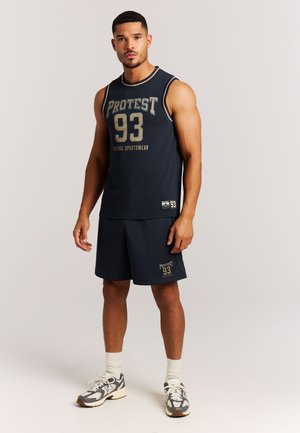 Marineblauw sporttanktop met gouden letters, gecombineerd met bijpassende shorts en sneakers met patroon. Voorzien van een atletische pasvorm en ademende stof.