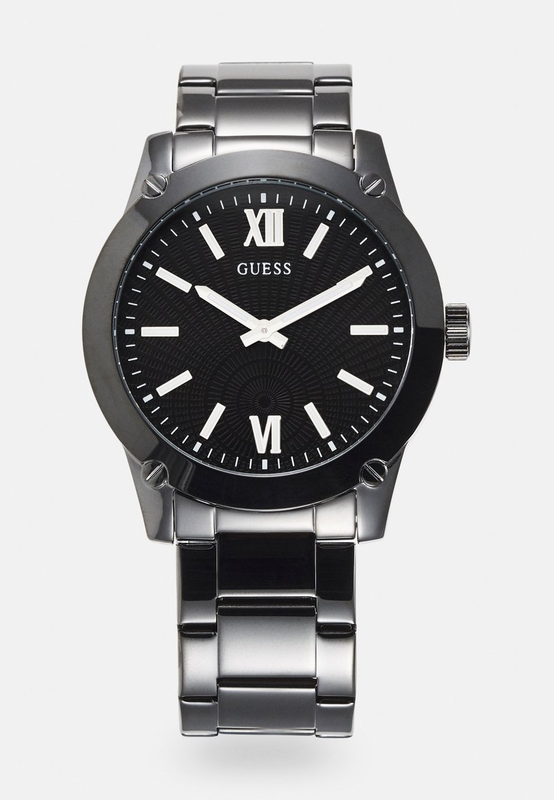 Schwarze Uhr mit rundem Ziffernblatt, silbernes Armband aus Edelstahl, römische Ziffern und ein gemusterter Zifferblatt. Markenname "GUESS" angezeigt.
