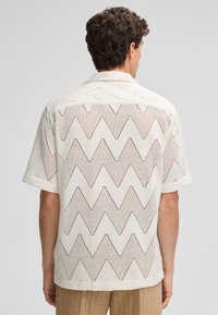 Korte mouwen overhemd in witte mesh met een zigzagpatroon en een relaxte pasvorm. Voorzien van een klassieke kraag en omgevouwen manchetten.