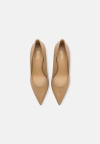 Escarpins en cuir tan à talons hauts avec des pointes effilées et une texture lisse. L'intérieur présente un logo embossé en or. Design minimaliste, sans accents supplémentaires.