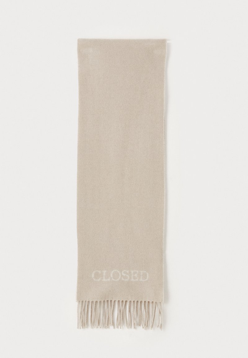 Sciarpa beige realizzata in tessuto morbido, con un dettaglio a frange nella parte inferiore e la parola "CLOSED" ricamata in leggero. Forma rettangolare.