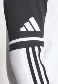 Felpa Adidas in tessuto nero con dettagli bianchi, design a tre strisce sulla manica e un grande logo bianco sulla spalla.
