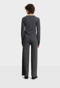 Maglione grigio a coste e pantaloni a gamba larga. Tessuto morbido, maniche lunghe e vestibilità comoda. Design minimalista senza motivi distintivi.