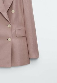 Lichtroze blazer van textuurstof, met een dubbelzijdig ontwerp, grote crème knopen en een enkele borstzak.