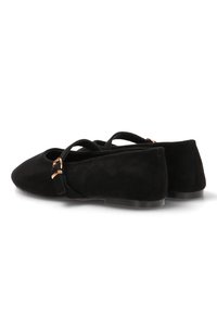 Bailarinas de ante negro con punta afilada, correas en el tobillo y acentos de hardware en tono dorado. Suela plana con una textura suave.