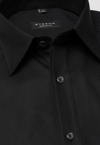 Sort ETERNA comfort-fit skjorte med klassisk krave, to sorte knapper og diskret grå syninger på en glat stofoverflade.