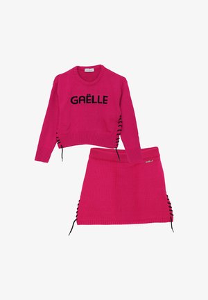 Set di maglione e gonna lavorato a maglia rosa con logo nero "GAËLLE". Dettagli accentuati laterali con lacci neri e texture a costine.