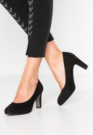 Czarne zamszowe szpilki z okrągłym noskiem i słupkowym obcasem. Buty mają gładką fakturę i elegancki, minimalistyczny design.