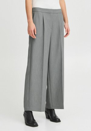 Grijze wijde broek van een gestructureerde stof met voorplooien. Voorzien van een middelhoge tailleband en gecombineerd met zwarte enkellaarsjes met hak.
