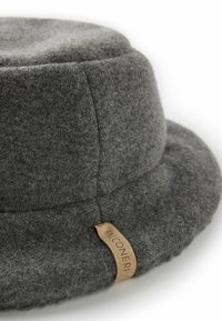 Szary filcowy kapelusz typu bucket o ukształtowanej formie, z widocznymi przeszyciami oraz skórzaną metką z wytłoczonym nazwą marki.