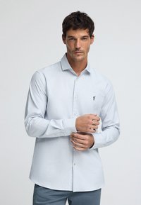 Camicia a quadri blu chiaro in cotone, con colletto button-down, maniche lunghe e un piccolo logo ricamato sul petto.