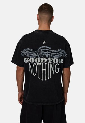 Zwart oversized T-shirt met een grafisch ontwerp van vleugels, een ster en de tekst "GOOD FOR NOTHING" in verweerde witte letters.