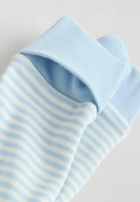 Svetlomodré bavlnené ponožky s rebrovaným lemom a striedavými bielymi pruhmi. Mäkká textúra, neformálny dizajn, zaoblená špička.