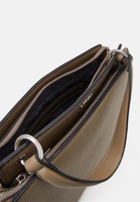 Sac à main en cuir brun texturé avec plusieurs compartiments, doublure intérieure noire et détails en matériel argenté. Les fermetures éclair améliorent la fonctionnalité.