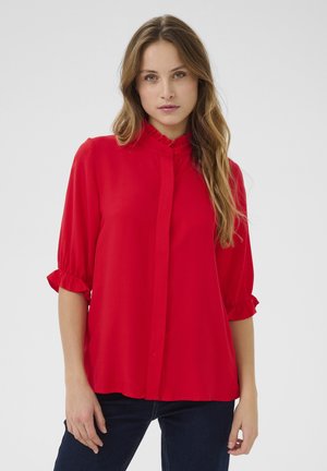 Blusa rossa con bottoni, colletto a volant e maniche a tre quarti. Tessuto morbido con una consistenza liscia e vestibilità comoda.