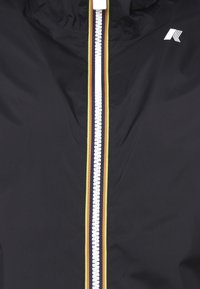 Giacca nera con zip, dotata di una zip bianca, caratterizzata da strisce gialle, rosse e arancioni a contrasto ai lati. Texture liscia e design con cappuccio.