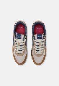 Sneakers featuring a combination of beige textile and brown suede; navy accents; cream laces; and a red interior with branding details.