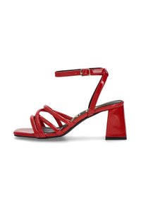 Las sandalias de charol rojo con tacón cuadrado presentan múltiples tiras entrecruzadas y una correa ajustable en el tobillo con una hebilla dorada.