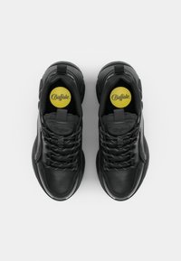 Svarta lädersneakers med rund tå, kraftig sula, texturerade detaljer och vitt spräckligt snörning. Gula märkta innersulor synliga.