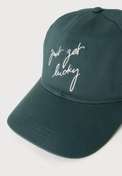 Casquette de baseball vert foncé avec une visière courbée et un texte brodé en blanc lisant "just get lucky" sur le panneau avant.
