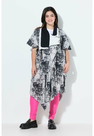 Asymmetriska svartvita mönstrade klänningen med korta ärmar, i kombination med livliga rosa leggings och kraftiga svarta platåskor.