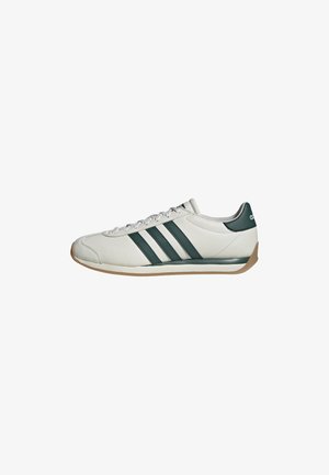 Baskets blanches avec des rayures Adidas vert foncé et languette au talon, semelle en caoutchouc, et lacets blancs, vues de côté sur un fond blanc.