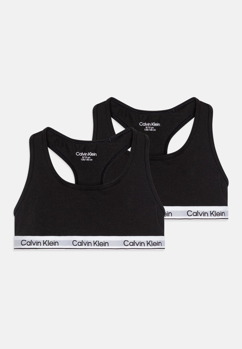 Dois soutiens desportivos pretos com um design de costas nadador, feitos de material macio, com uma faixa branca da Calvin Klein na parte inferior.