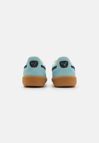 Zapatillas deportivas de ante en azul claro con suela de goma. Acentos en azul marino en la parte trasera y laterales, con un pequeño logotipo en el talón.