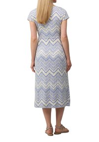 Abito midi con un motivo a zigzag in viola, bianco e verde. Maniche a cappuccio e vestibilità rilassata. Indossato con sandali con cinturini.