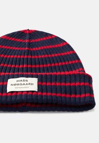 Berretto lavorato a maglia con strisce orizzontali blu navy e rosse. Presenta un risvolto con un'etichetta che mostra "MADS NØRGAARD COPENHAGEN."