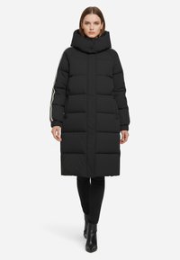 Giacca a vento nera con colletto alto, design trapuntato e zip laterali. Presenta strisce a contrasto sulle maniche e lunghezza lunga.