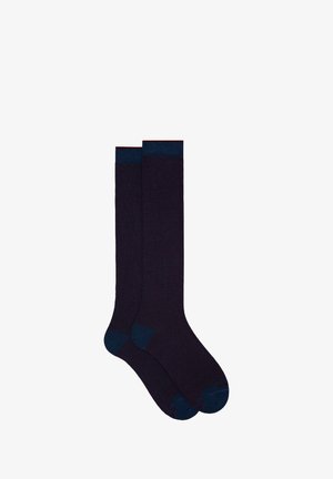 Kniestrümpfe in Dunkellila mit strukturiertem Ribbenmuster. Kontrastierende dunkelblaue Akzente an Bund und Zehen. Hergestellt aus weichem, elastischem Material.