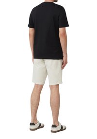 Zwarte katoenen T-shirt, korte mouwen, gecombineerd met witte shorts en witte sneakers met zwarte accenten. Zichtbare stiksels en een klassieke pasvorm.
