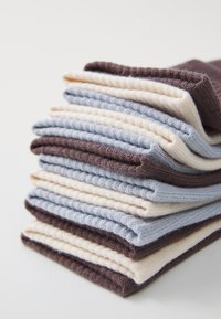 Stack of knit socks in brown, light blue, and cream colors. Features varying textures with ribbed patterns along the edges.
