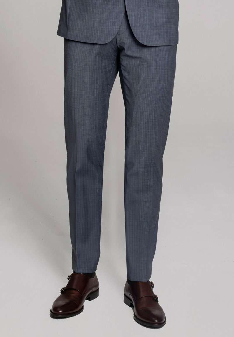 Szare spodnie garniturowe o delikatnym wzorze w kratę, gładkiej teksturze i dopasowanym kroju, zestawione z wypolerowanymi brązowymi skórzanymi butami.