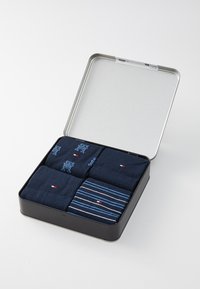 Set aus vier dunkelblauen Socken in einer silbernen Dose. Enthält einfarbige und gestreifte Designs mit kleinen Logo-Akzenten.