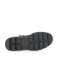 Black rubber shoe sole featuring a patterned tread with deep grooves. The base is flat with a slight curve at the toe for traction.