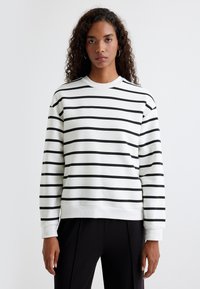 Sudadera blanca con rayas horizontales negras, cuello redondo acanalado y mangas largas con puños; tejido de algodón suave; ajuste relajado.