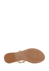 Sandal transparente con tiras, que presenta una suela de goma marrón con un agarre texturizado. Incluye acentos decorativos cerca de las tiras.