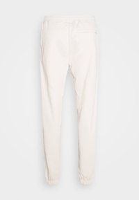 Vita avsmalnande joggerbyxor med resår i midjan, bakficka på höger sida och resår i bensluten.